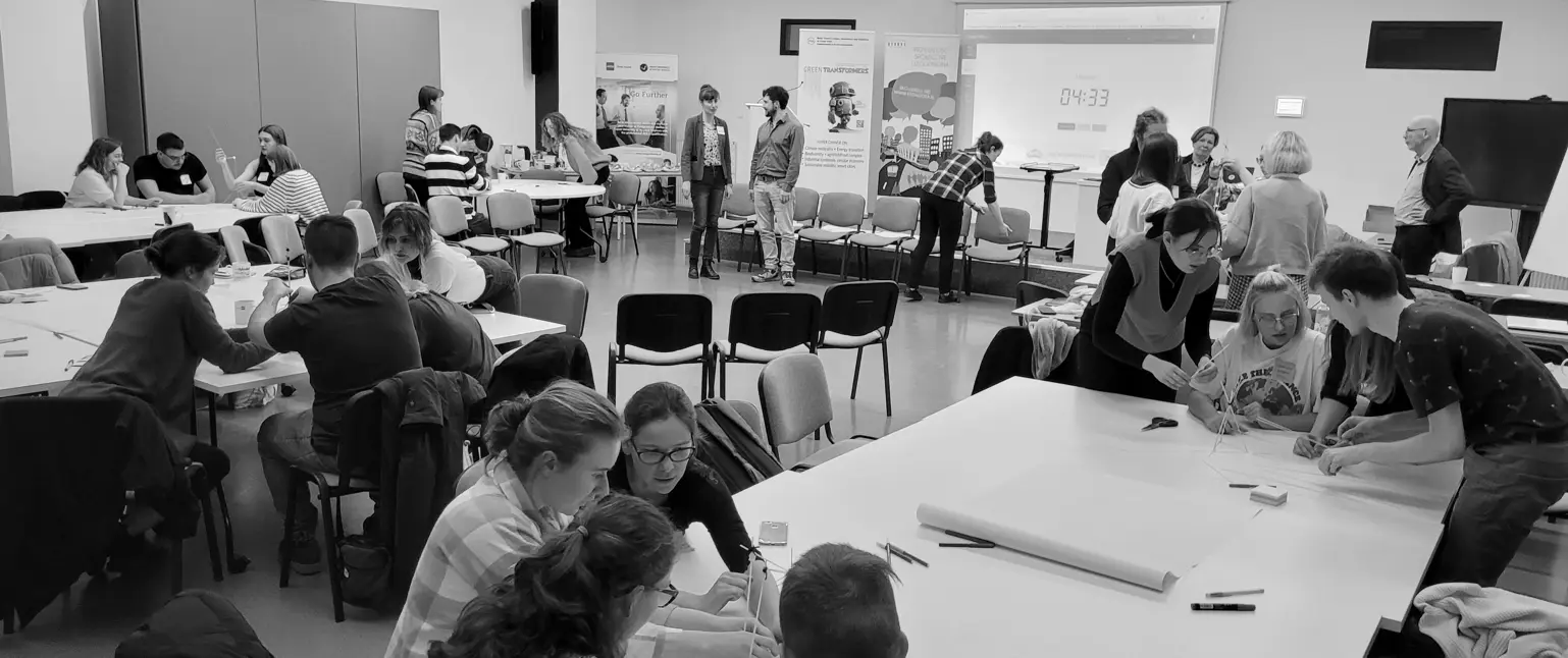 Uczestnicy warsztatu w dużej sali pracują w grupach.